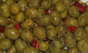Angeschlagene grüne Oliven mit roter Chili, Oregano und Samen von wildem Fenchel