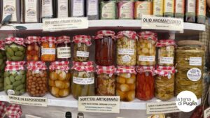 Regal mit handwerklichen Konserven aus Apulien: Gemüse in Öl, Oliven und natives Olivenöl extra